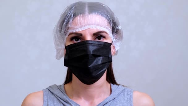Пациентка в одноразовой кепке снимает черную защитную маску. Понятие гигиены. предотвратить распространение микробов и бактерий и избежать заражения вирусом короны — стоковое видео