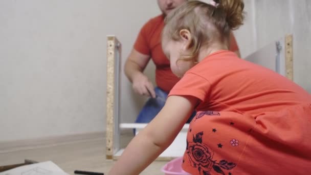 Papá colecciona muebles blancos para el hogar. Hija ayuda a papá a recoger muebles . — Vídeos de Stock