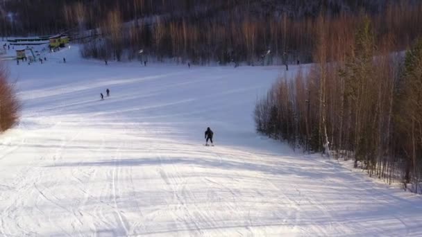 Skier γλιστρήσει κάτω από την κορυφή του βουνού σε μια ηλιόλουστη μέρα του χειμώνα. Θέα της περιοχής. Η έννοια του σκι. — Αρχείο Βίντεο