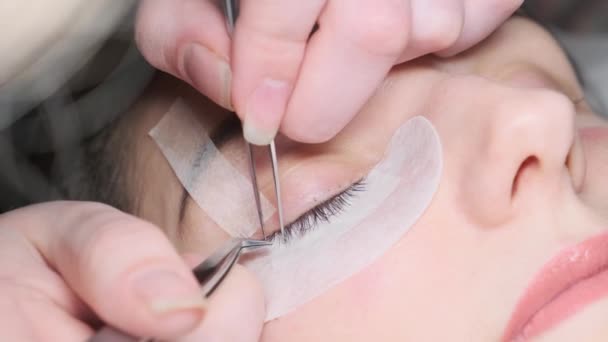 Διαδικασία επέκτασης βλεφαρίδων. Τσιμπιδάκι ψεύτικο μακριές βλεφαρίδες όμορφα γυναικεία μάτια — Αρχείο Βίντεο