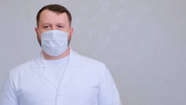 Homem com uma máscara protetora e uma camisa branca olha para a câmera, close-up. Conceito de higiene. prevenir a propagação de germes e bactérias e evitar a infecção com o vírus da coroa. espaço de cópia — Fotografia de Stock