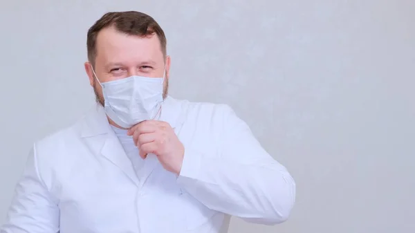 Homem em uma máscara protetora e uma camisa branca olha para a câmera, close-up. Conceito de higiene. prevenir a propagação de germes e bactérias e evitar a infecção com o vírus da coroa. espaço de cópia — Fotografia de Stock