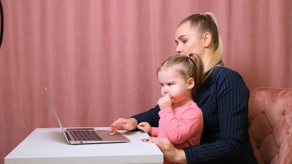 Giovane bella bionda e la sua affascinante figlioletta stanno facendo shopping online con un computer portatile e carta di credito. Shopping nel negozio online . — Foto Stock