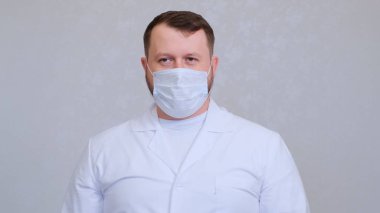 Koruyucu maskeli ve beyaz gömlekli bir adam kameraya bakıyor, yakından. Hijyen konsepti. Mikrop ve bakterilerin yayılmasını önlemek ve taç virüsünün bulaşmasını önlemek. Boşluğu kopyala