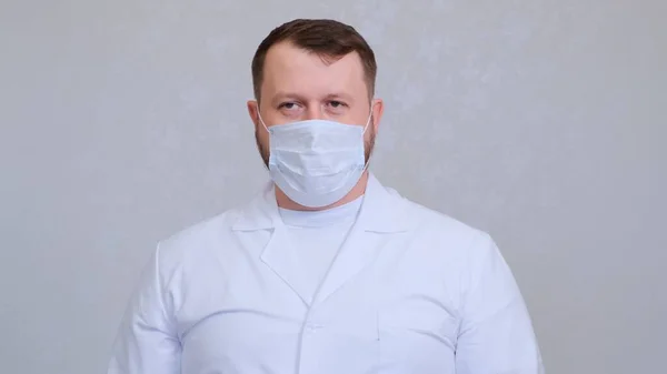 Homem com uma máscara protetora e uma camisa branca olha para a câmera, close-up. Conceito de higiene. prevenir a propagação de germes e bactérias e evitar a infecção com o vírus da coroa. espaço de cópia — Fotografia de Stock