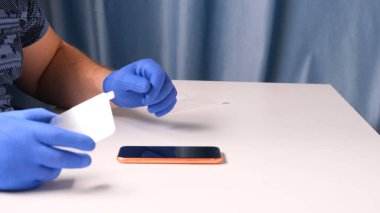 Mavi eldivenli erkek elleri, kırık cam ekran koruyucunun yerine akıllı telefon koyuyor. Bir adam cam değiştirmek için akıllı telefon hazırlar. Akıllı telefon tamir konsepti. Boşluğu kopyala