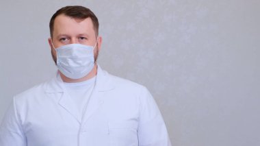 Koruyucu maskeli ve beyaz gömlekli bir adam kameraya bakıyor, yakından. Hijyen konsepti. Mikrop ve bakterilerin yayılmasını önlemek ve taç virüsünün bulaşmasını önlemek. Boşluğu kopyala