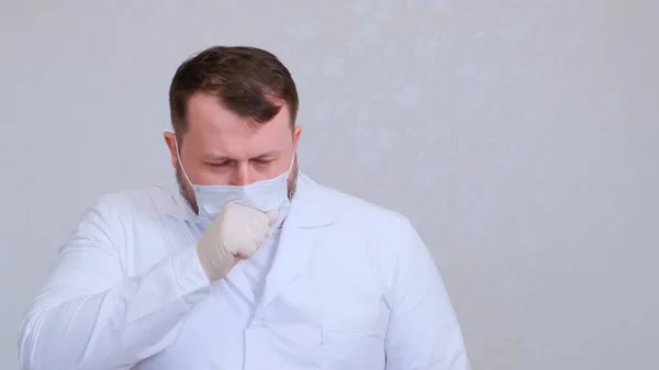 Lékař samec kašle v ochranné masce infikované virem nebo koronavirem. — Stock fotografie