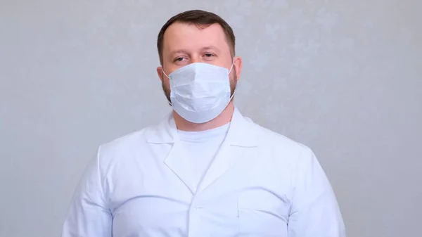 Homem com uma máscara protetora e uma camisa branca olha para a câmera, close-up. Conceito de higiene. prevenir a propagação de germes e bactérias e evitar a infecção com o vírus da coroa. espaço de cópia — Fotografia de Stock