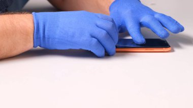 Mavi eldivenli erkek elleri, kırık cam ekran koruyucunun yerine akıllı telefon koyuyor. Bir adam cam değiştirmek için akıllı telefon hazırlar. Akıllı telefon tamir konsepti. Boşluğu kopyala