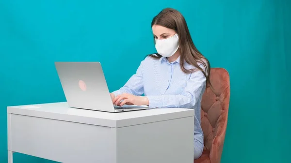 Frau, die zu Hause mit medizinischer Maske im Gesicht arbeitet. Coronavirus Quarantäne Remote Home Arbeitskonzept. — Stockfoto