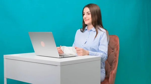 Feminino no link de vídeo em um laptop mostra uma apresentação para uma máscara médica protetora, tentando vendê-lo, no local de trabalho ou em casa durante uma pandemia. O conceito de quarentena e auto-isolamento — Fotografia de Stock