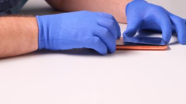 Mavi eldivenli erkek elleri, kırık cam ekran koruyucunun yerine akıllı telefon koyuyor. Bir adam cam değiştirmek için akıllı telefon hazırlar. Akıllı telefon tamir konsepti. Boşluğu kopyala