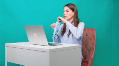 Dizüstü bilgisayardaki video bağlantısındaki kadın koruyucu bir tıbbi maskenin sunumunu gösteriyor, bunu iş yerinde ya da evde salgın sırasında satmaya çalışıyor. Karantina ve kendini izole etme kavramı.