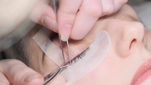 Il concetto di bellezza. Processo di estensione delle ciglia. Maestro pinzette finte lunghe ciglia bellissimi occhi femminili . — Video Stock