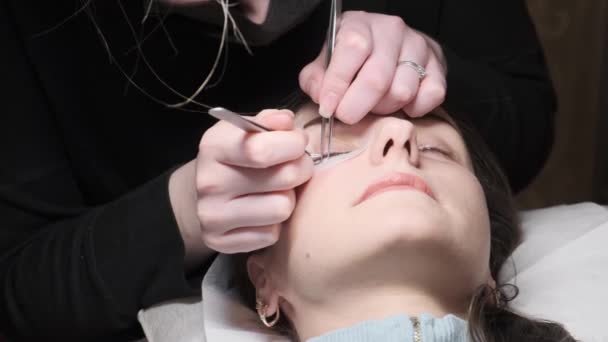 Procedimento de extensão das pestanas. Mestre pinças falsos longos cílios belos olhos femininos — Vídeo de Stock