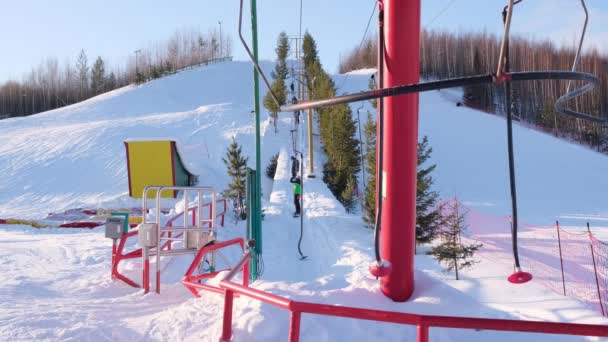 St. Petersburg, Rusland - 12 januari 2020: Skiliften tijdens een zonnige winterdag. Skiërs en snowboarders beklimmen de berg met een skilift — Stockvideo