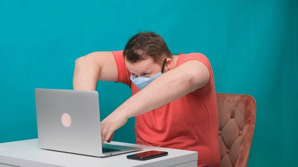 Dizüstü bilgisayar kullanan komik erkek kareleri. Korumalı sağlık maskesi takmış bilgisayar başında hacker gibi davranan bir adam.. — Stok fotoğraf
