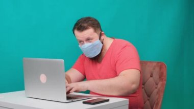 Dizüstü bilgisayar kullanan komik erkek kareleri. Korumalı sağlık maskesi takmış bilgisayar başında hacker gibi davranan bir adam..