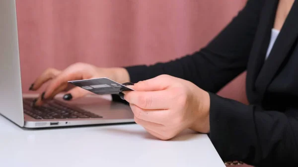 Manos femeninas hacer una compra en Internet utilizando un ordenador portátil, pago con tarjeta, primer plano . —  Fotos de Stock