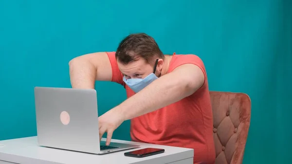 Забавні рамки чоловічої статі використовують ноутбук. людина працює на комп'ютері в захисній медичній масці, прикидаючись хакером . — стокове фото