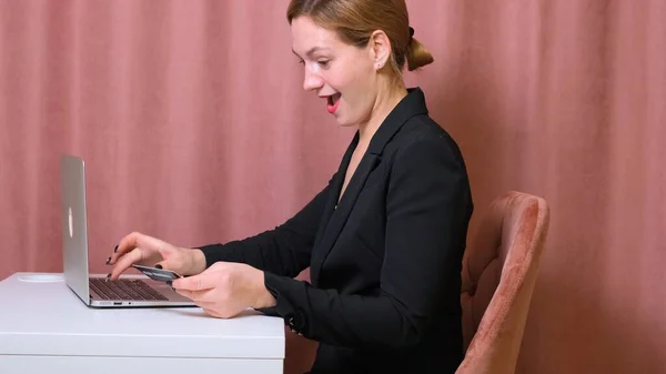 Fêmea fazer uma compra na Internet usando um laptop, pagamento por cartão, close-up. mulher está surpreso — Fotografia de Stock