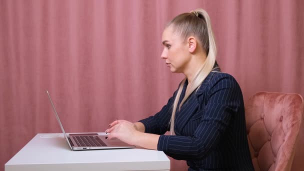 Серйозна жіноча секретарка, що друкує на ноутбуці, сидить за столом на своєму робочому місці . — стокове відео