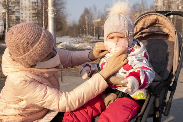 Dziewczyna z dzieckiem stoi na drodze w ochronnej masce medycznej. Gęsty smog na ulicach. Epidemia grypy. — Zdjęcie stockowe