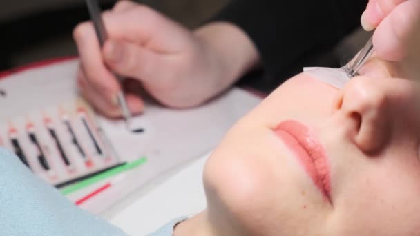 Eyelash extension procedure. Master tweezers fake long lashes beautiful female eyes — Stock Video