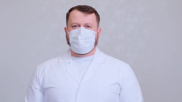 Egy férfi védő maszkban és fehér ingben a kamerába néz, közelről. Higiéniai koncepció. megakadályozza a baktériumok és baktériumok terjedését, és elkerüli a koronavírussal való fertőződést. másolás helye — Stock videók
