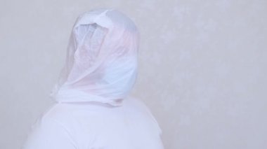 Kafasında torba olan bir erkek ve koruyucu maskeli bir erkek çataldan pirzola yapıyor. Enfeksiyon korkusu. Coronavirüs COVID-19 salgını, evde kendini izole etme ve karantina. 