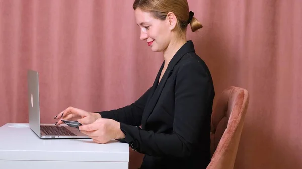Kvinna gör ett köp på Internet med hjälp av en bärbar dator, betalning med kort, närbild. — Stockfoto