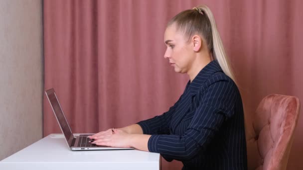 Femme utilise un ordinateur portable alors qu'elle est assise à son bureau. Une jeune femme d'affaires européenne est assise au bureau et travaille sur un logiciel pour ordinateur portable . — Video