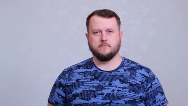 El gordo barbudo cansado con una camiseta azul enrolla sus ojos. Estaba cansado del trabajo o de escuchar la conversación de sus esposas. — Vídeos de Stock