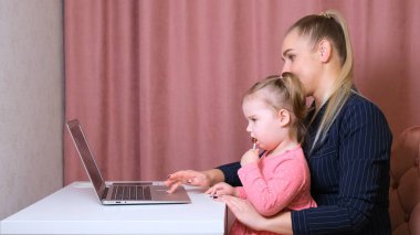 Çalışan anne ev ofisinden çalışıyor. Mutlu anne ve kız gülümsüyor. Başarılı bir kadın ve dizüstü bilgisayar kullanan tatlı bir çocuk. Serbest çalışan işyeri. Kadın işi işte. Kolay değil ama o bu göreve uygun.