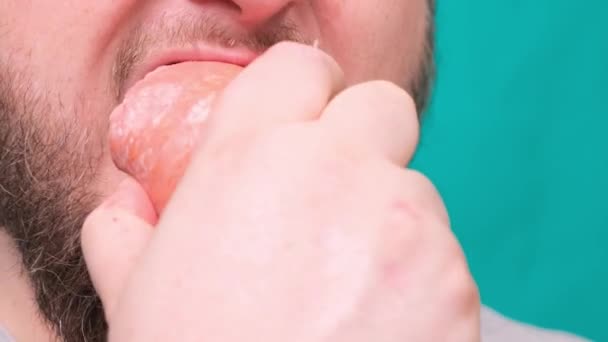 Бородатый человек кусает большую колбасу салями на зеленом фоне. Концепция диеты провалилась, сила воли в питании, вредная пища — стоковое видео