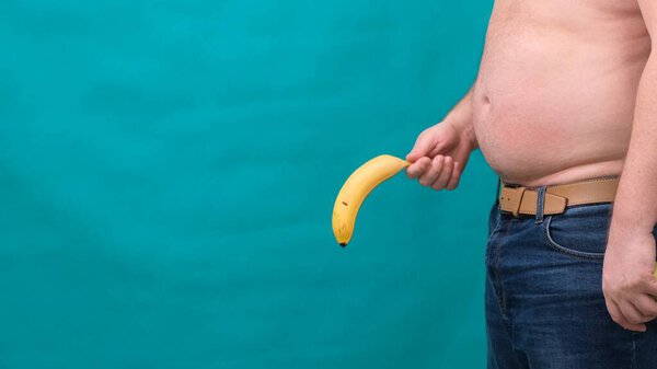 old limp drooping banana hanging from genital area of clothed unrecognizable man, impotence erectile dysfunction or limp-dick concept.