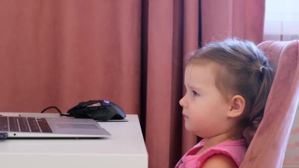 Gyönyörű, aranyos, szomorú kislány egy laptopnál. A koncepció a gyermekek számítógépes játékoktól, rajzfilmektől és kütyüktől való függésének. — Stock videók
