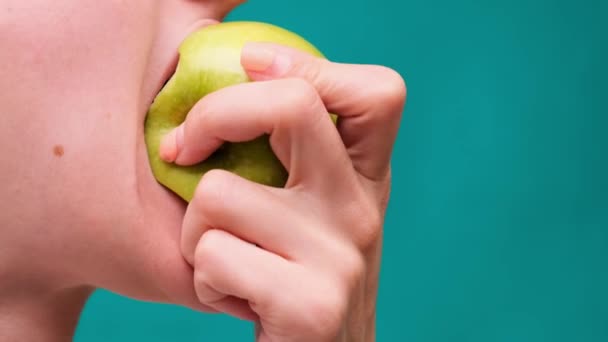 Alimentação saudável e dentes saudáveis ou dieta, jovem morde uma maçã fresca em uma tela verde close-up — Vídeo de Stock