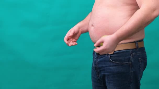 Hombre gordo con un vientre grande sostiene una manzana verde y un plátano en sus manos. El concepto de alimentación saludable y pérdida de peso, dieta . — Vídeo de stock