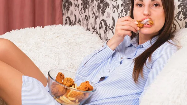 젊고 행복 한 여자가 튀긴 치킨을 먹고 있어. 여자들은 닭 날개를 먹고, 칼로리 섭취와 건강 상의 위험, 콜레스테롤 섭취 — 스톡 사진