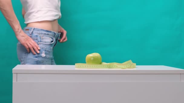 Pancia dimagrita femminile e mela verde in primo piano, messa a fuoco selettiva. Il concetto di perdita di peso e corretta alimentazione — Video Stock