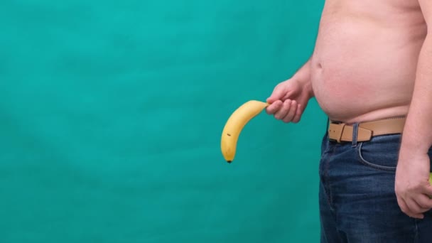 服を着たまま認識できない男、インポテンツ勃起不全、あるいはぐったりディック概念の性器からぶら下がっている古いぐったり垂れバナナ. — ストック動画