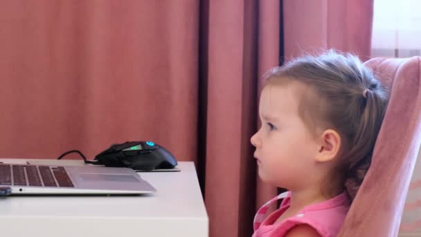 Bella carina bambina triste ad un computer portatile. Il concetto di dipendenza dei bambini da giochi per computer, cartoni animati e gadget . — Video Stock