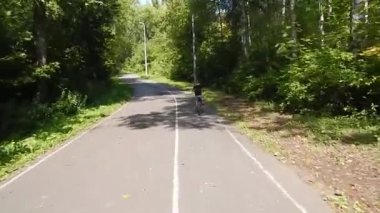 Çocuk parkın asfalt yolunda bisiklet sürüyor..