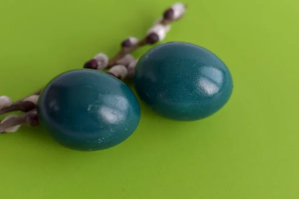 Пасхальные яйца и ветви киски-ивы с листьями на зеленом столе . — стоковое фото