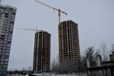 İki yüksek bina ve inşaat halindeki kule vinçleri.