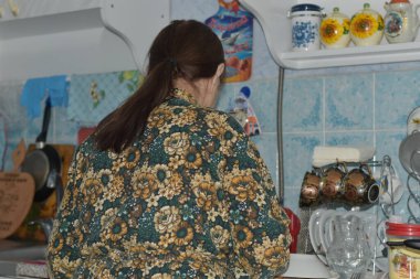 Mutfakta renkli ceketli bir kadın var..