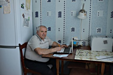 Evde karantinaya alınmış bir iş. Coronavirus. Bir adam bilgisayarda çalışıyor..