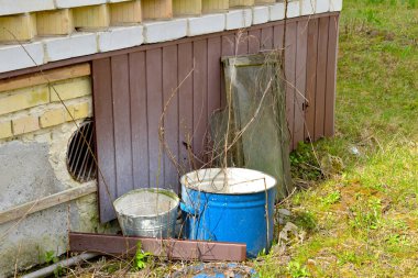 Kırsal alan. Eski saksılar, kovalar evin yanında duruyor..